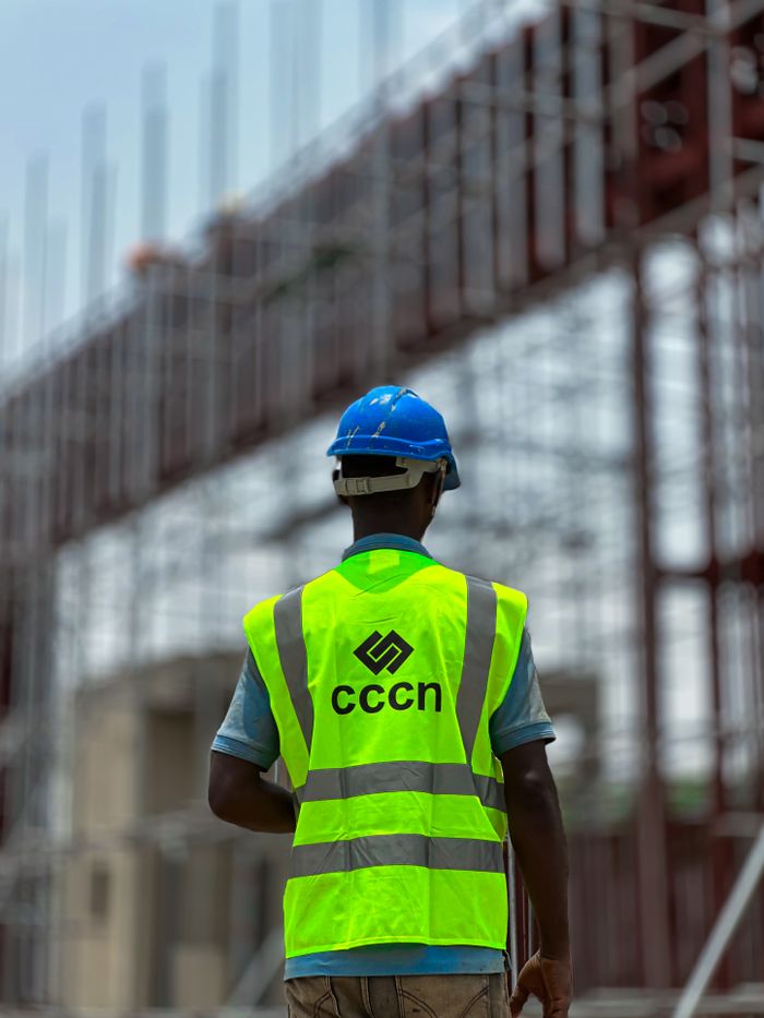 A construction worker in a neon vest and hard hat on a building site, emphasizing safety.