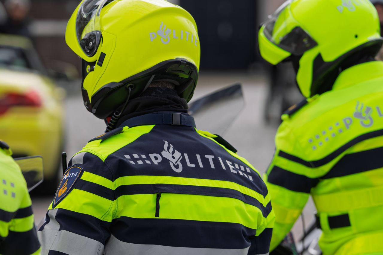 Dutch police officers in reflective uniforms seen from behind, perfect for law enforcement themes.
